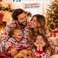Une famille souriante en pyjamas de Noël posant ensemble devant un sapin illuminé.